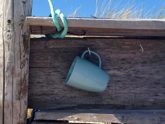 Türkisfarbene Tasse hängt an einem Haken an einer Holzwand