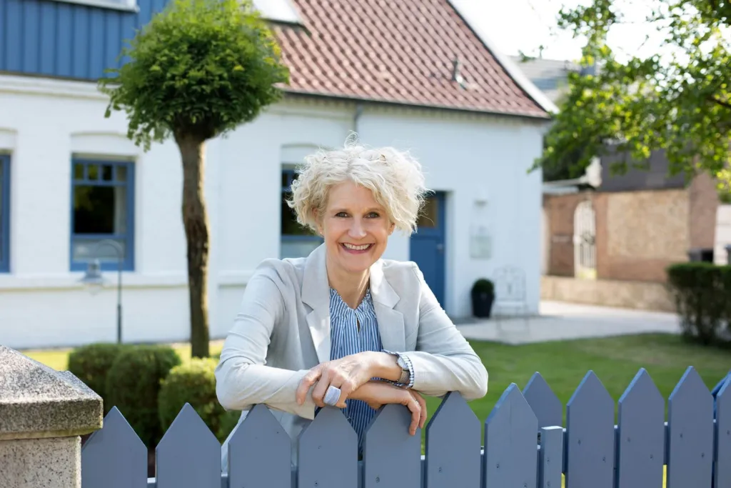 Ellen Buttgereit an einem Gartenzaun vor ihrem Haus