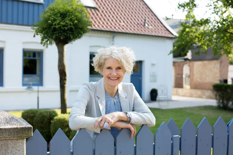 Ellen Buttgereit an einem Gartenzaun vor ihrem Haus