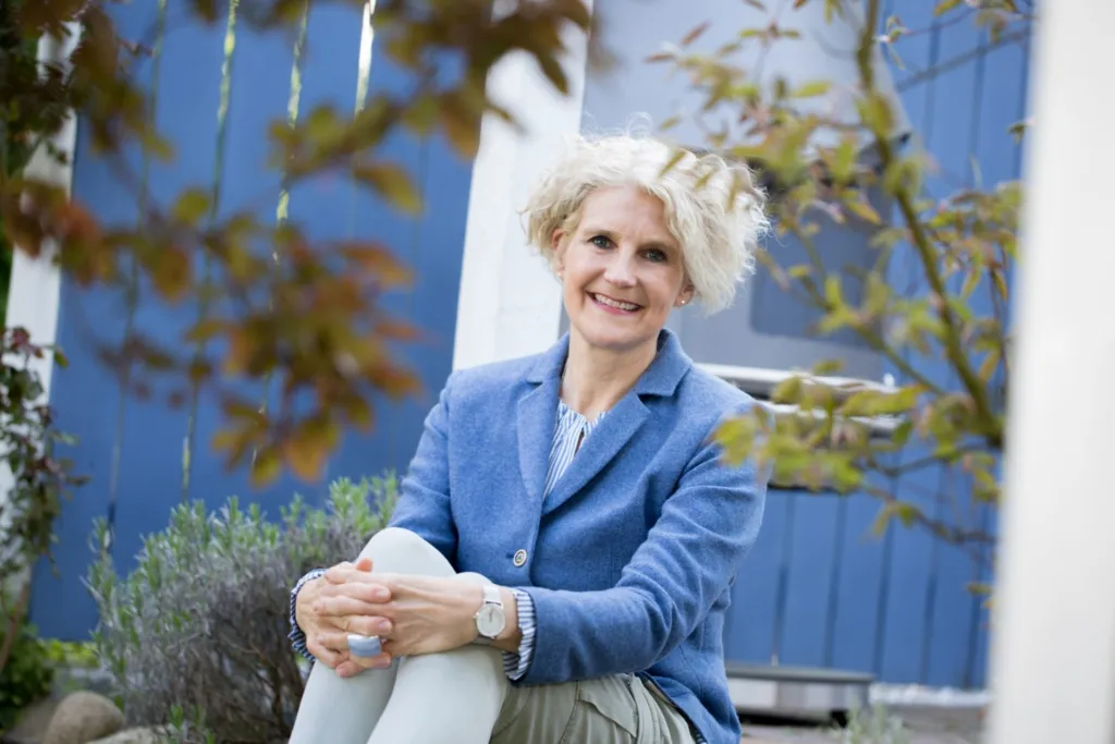 Ellen Buttgereit sitzt vor einem blauen Zaun