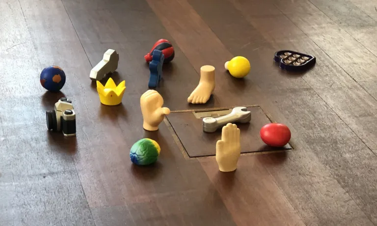 Kleine Figuren und Symbole auf einem Holzboden, ausgelegt für eine Coaching-Übung