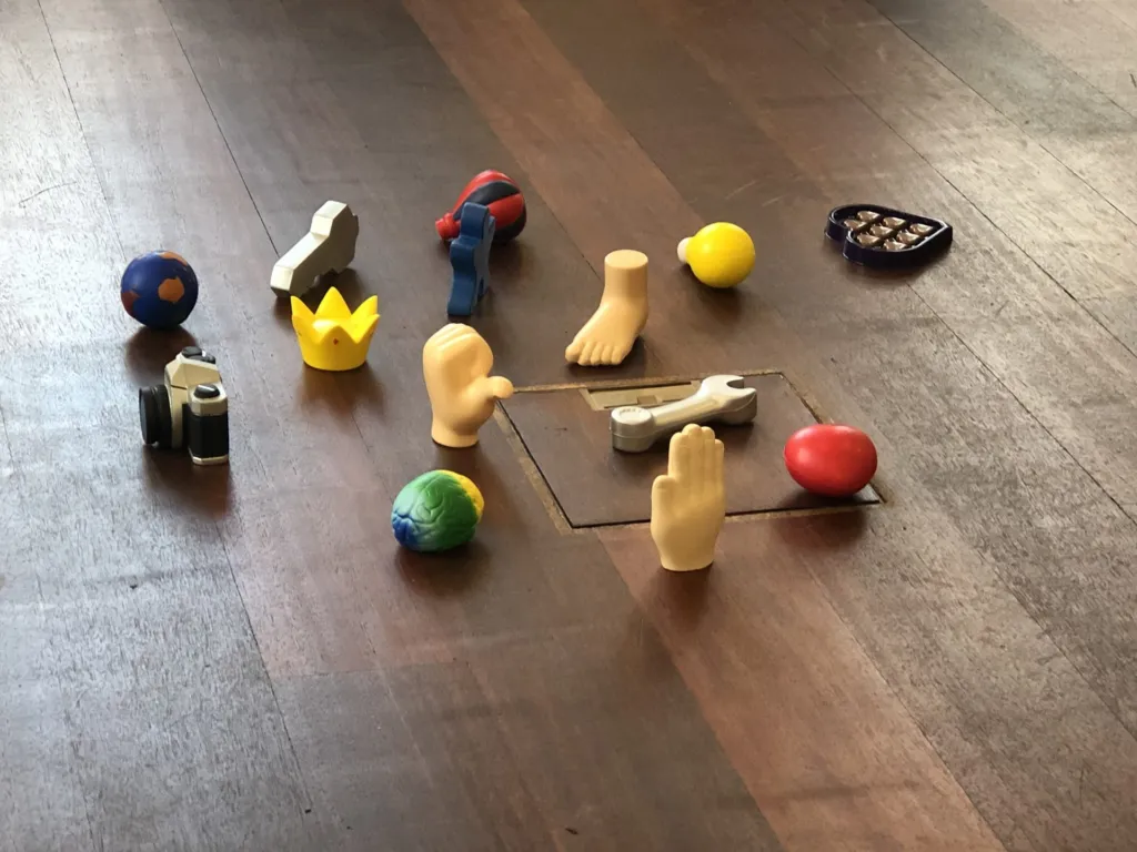 Kleine Figuren und Symbole auf einem Holzboden, ausgelegt für eine Coaching-Übung