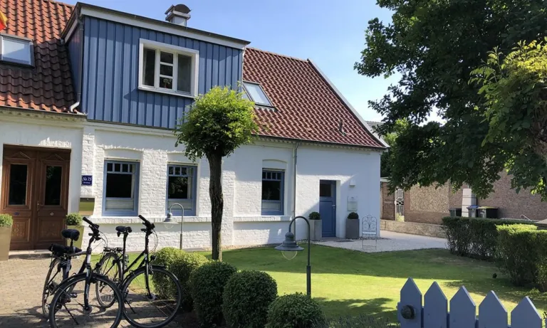Weißes Haus mit blau verkleidetem Obergeschoss und Garten, Sitz der Coachingräume